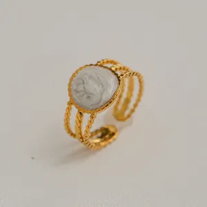 Détail macro d'une bague dorée ajustable avec incrustation marbre blanc et triple anneau