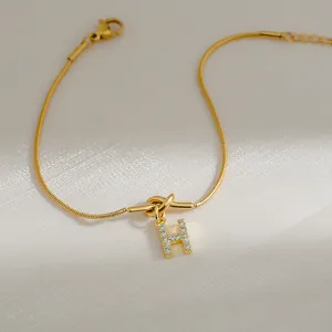 Detail van 18k vergulde slangenketting armband met sprankelende letter H-hanger