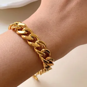 Dettaglio di un bracciale a catena cubana dorata al polso con finitura lucida a specchio
