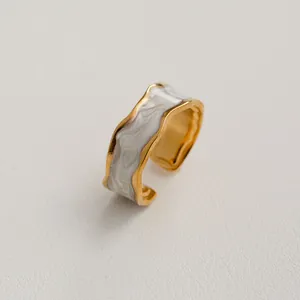Vue détaillée d'une bague en acier doré avec finition en émail marbré blanc élégant