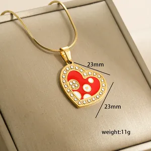 Macro detail of 14k gold heart pendant with red enamel, measuring 23mm and weighing 11g
