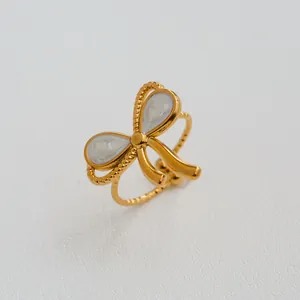 Détail macro de la bague nœud dorée avec émail blanc et anneau à texture torsadée