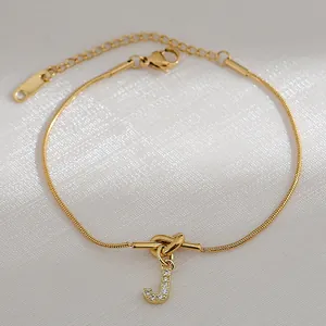 Macro-opname van de gouden slangenketting armband met sprankelende letter J hanger en knoopje