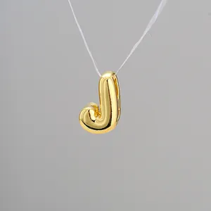 Macro shot of 3D balloon letter J pendant in gold finish with mirror polished surface