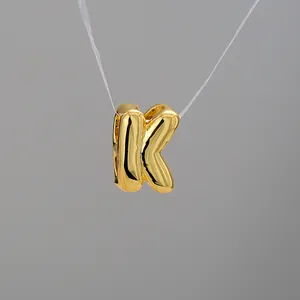 Detailed view of balloon-style letter K pendant in polished gold finish and shiny metal