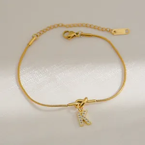 Detail van een 18k vergulde knooparmband met een sprankelende zirkonia letter K-hanger