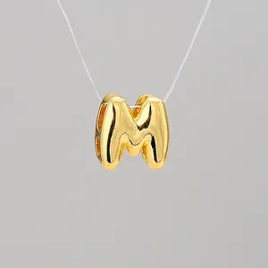 Macro shot of 18K gold plated bubble letter M pendant with high polish metal finish