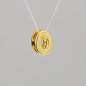 Macro detail of gold-plated hollow H-shaped pendant with a polished shiny finish