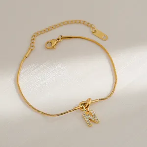 Macro detail van 18k goud vergulde slangenarmband met hanger letter N en zirkonia