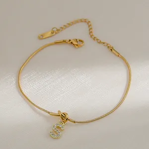 Detail van gouden slangenketting armband met sprankelende strass letter S hanger