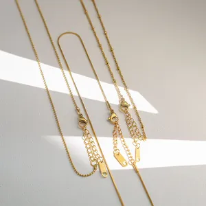 Macro shot of gold snake chains and beaded necklaces with lobster clasps and steel tags