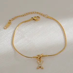 Detail van 18k vergulde slangenketting armband met knoopontwerp en zirkoon X-hanger
