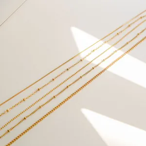 Detail of five assorted 18K gold-plated snake and bead chains with elegant light shadow