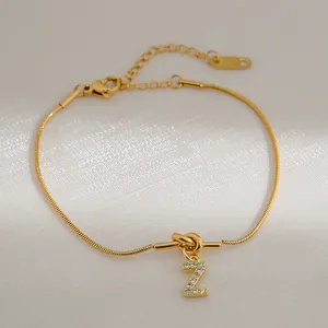 Detail van 18k vergulde knooparmband met zirkoon letter Z hanger en gladde slangenketting