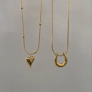 Luxuriöse goldene Halsketten mit U-Form und Herzanhänger vor neutralem grauem Hintergrund