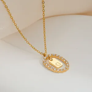 Dettaglio della collana placcata oro con pendente ovale, zirconi e incisione lettera G