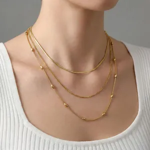 Three-layer layered necklace in gold finish with snake chain and bead accents on model