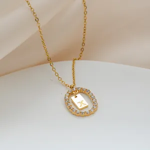 Dettaglio macro della collana dorata con anello in zircone e pendente con lettera X