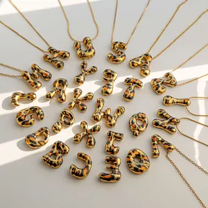 Collares de letras doradas con colgantes de esmalte de leopardo en fondo minimalista