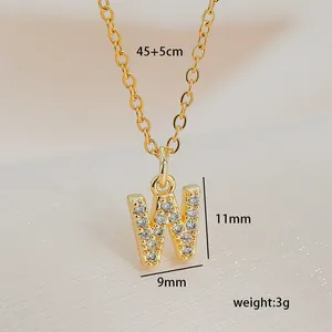Macro shot of gold square pendant with letter W and cubic zirconia on silk background