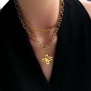 Detail of gold double-layer cross pendant necklace with toggle clasp on mannequin