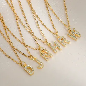 Gold square alphabet necklaces with micro-paved zircons on elegant silk background