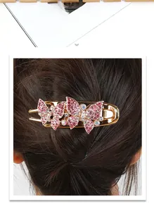 Macro detail of golden butterfly hair claw clip with sparkling pink rhinestones