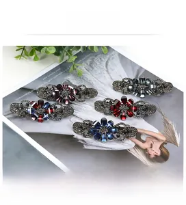 Detail view of five floral rhinestone hair clips in assorted colors on a magazine background
