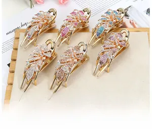 Close-up of sparkling rhinestone hair clips with colorful leaf patterns on a wooden tray