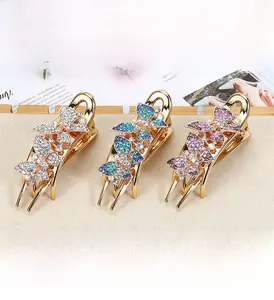 Detail of elegant butterfly hair claws with colorful rhinestones on a beige display mat
