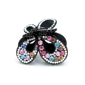 Pince à cheveux papillon étincelante avec strass colorés sur une base noire élégante