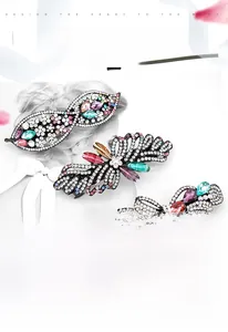Detailed close-up of hollow alloy bow hair clips with colorful rhinestones on a magazine