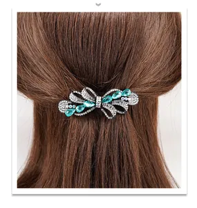 Detail of bow hair clip with blue water-drop gems and rhinestones on brown hair