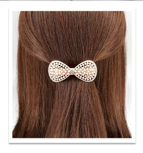 Detail of white pearl bow hair clip with rhinestones worn on long brown hair