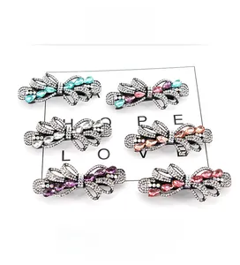 Detail view of six bow-shaped hair clips featuring colorful rhinestones and black alloy base