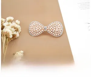 Close-up of rose gold bow hair clip with white pearls and rhinestones on a card