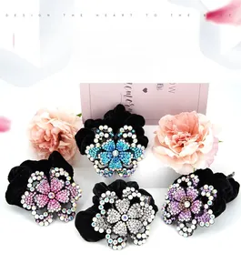 Detailed view of velvet scrunchies with large rhinestone floral charms in four colors