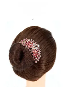Detailed view of a gold peacock hair comb with pink rhinestones on a brown hair bun