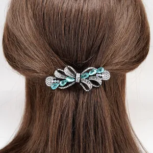 Elegant bow hair clip with blue crystals and rhinestones on dark brown hair