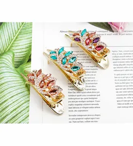 Macro shot of three luxury gold-toned floral hair clips with sparkling marquise crystals