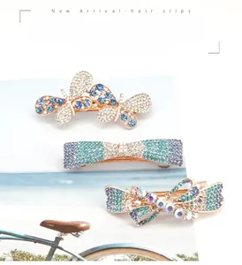 Detail view of crystal bow spring hair clips with blue rhinestones on gold base