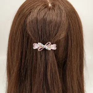 Elegant bow hair clip with pink rhinestones shown on brown hair for styling view