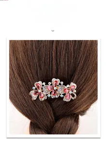 Close-up of golden hair comb with red crystals and floral design in dark hair