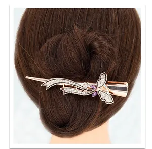 Détail d'une pince à cheveux papillon or rose avec strass brillants et pierres violettes