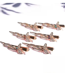 Détail de barrettes papillon en or rose avec strass étincelants et cristaux colorés