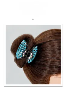 Détail d'une pince à cheveux noire avec strass bleus sur des cheveux bruns