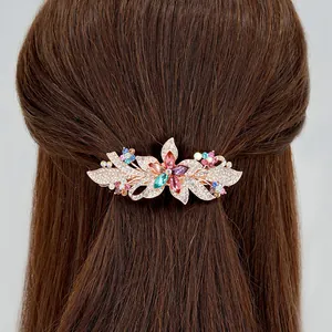 Elegant rose gold flower hair clip with colorful rhinestones on brown hair background