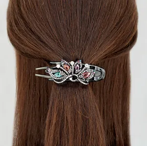 Elegant peacock flower hair claw clip with colorful rhinestones on dark hair
