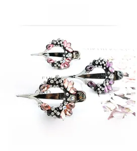 Detail of three crystal hair clips with vine and heart patterns in purple and gold