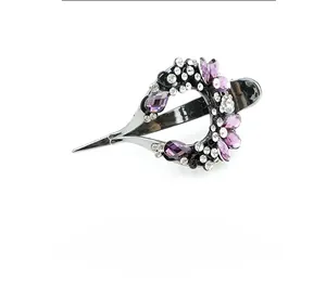 Detail view of vine-shaped hair clip with purple crystal rhinestones and dark metal finish